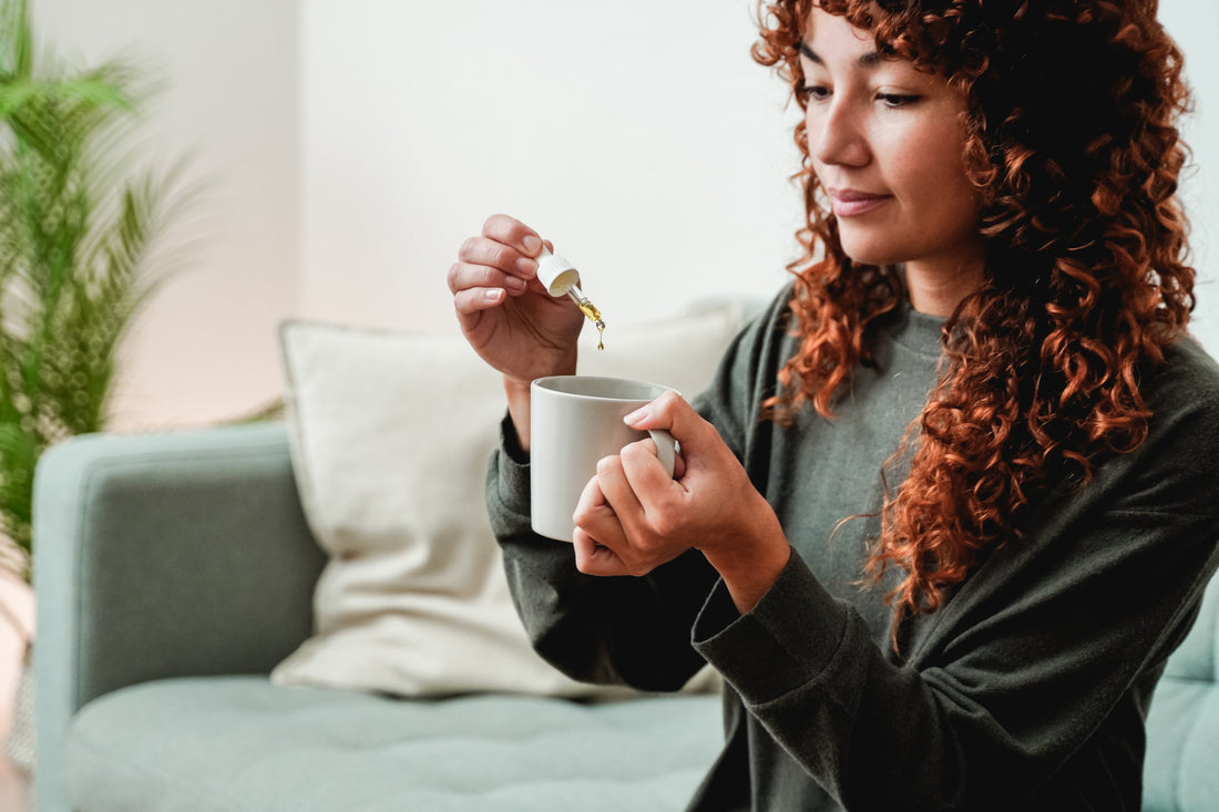 A person adding CBD tincture to a drink