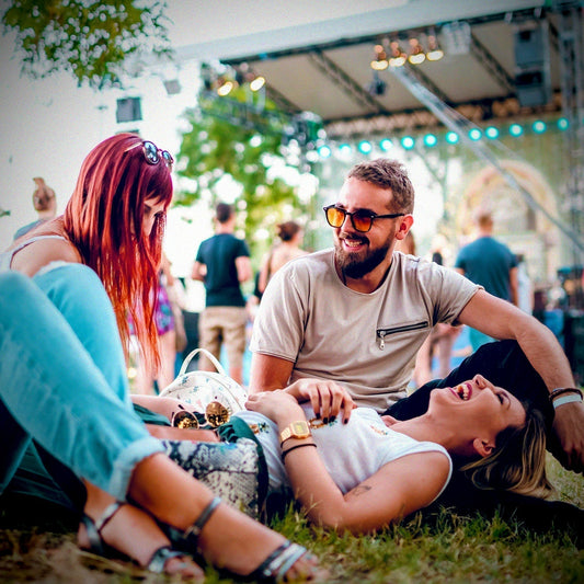 People laughing as they sit on the grass at a concert