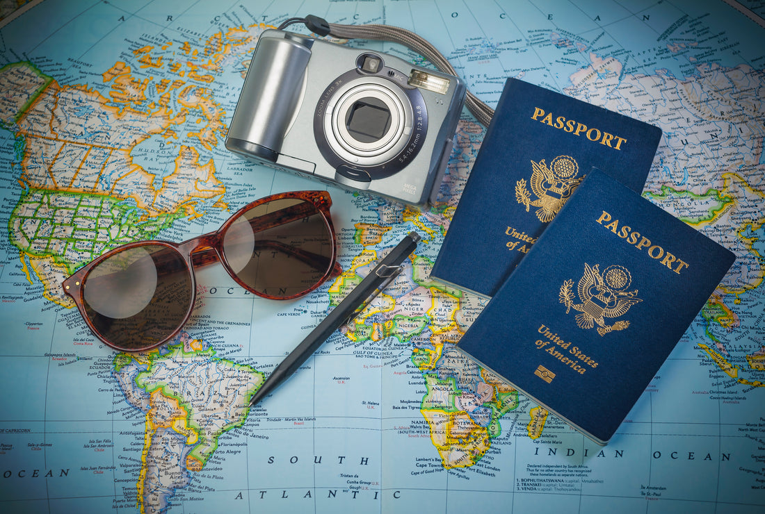 Two passports, a camera, and sunglasses placed on a world map