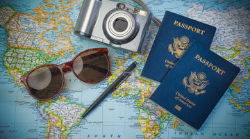 Two passports, a camera, and sunglasses placed on a world map