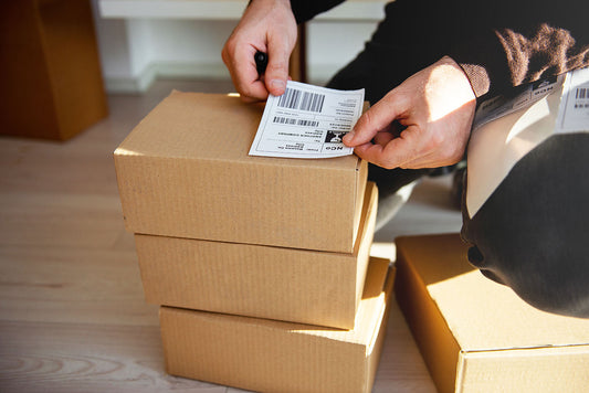 A person putting a shipping label on a package